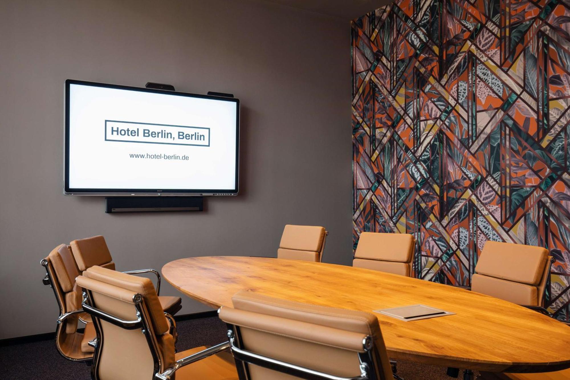 Hotel Berlin, Berlin, A Member Of Radisson Individuals Buitenkant foto The image shows a modern conference room. It features a large oval wooden table surrounded by several beige chairs. On one wall, there is a large screen displaying the text "Hotel Berlin, Berlin" along with a website URL. Another wall has a colorful 