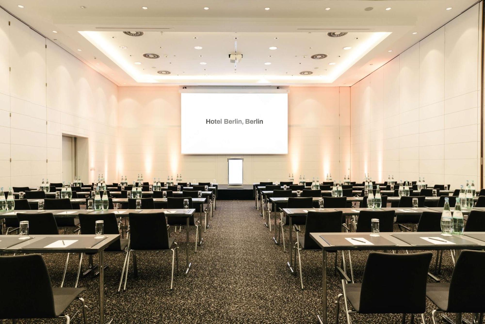 Hotel Berlin, Berlin, A Member Of Radisson Individuals Buitenkant foto The image shows a conference room or meeting space set up for an event. The room features multiple rows of tables and chairs, all arranged for participants. At the front of the room, there is a large screen displaying the text "Hotel Berlin, Berlin."