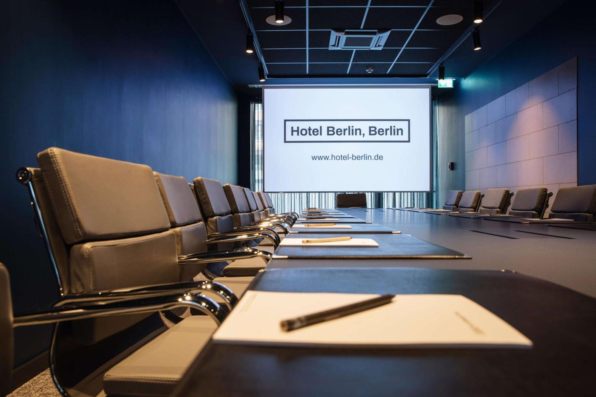 Hotel Berlin, Berlin, A Member Of Radisson Individuals Buitenkant foto The photo shows a modern conference room. In the foreground, there are several sleek black chairs arranged around a large rectangular table. On the table, there are notebooks and pens placed neatly for participants. At the end of the room, there's a 