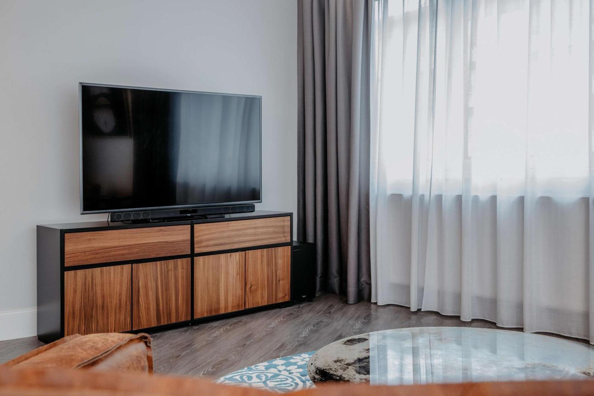 Hotel Berlin, Berlin, A Member Of Radisson Individuals Buitenkant foto A living room with a flat screen television and a wooden cabinet.